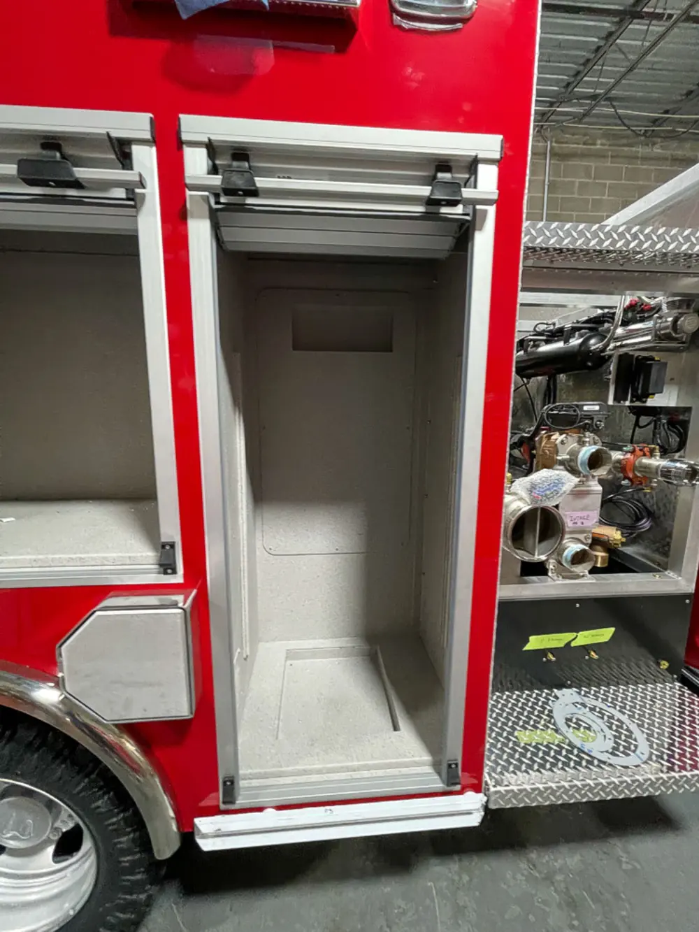 Exterior view of small fire truck showing cab, body compartments, and wheel/tire area.
